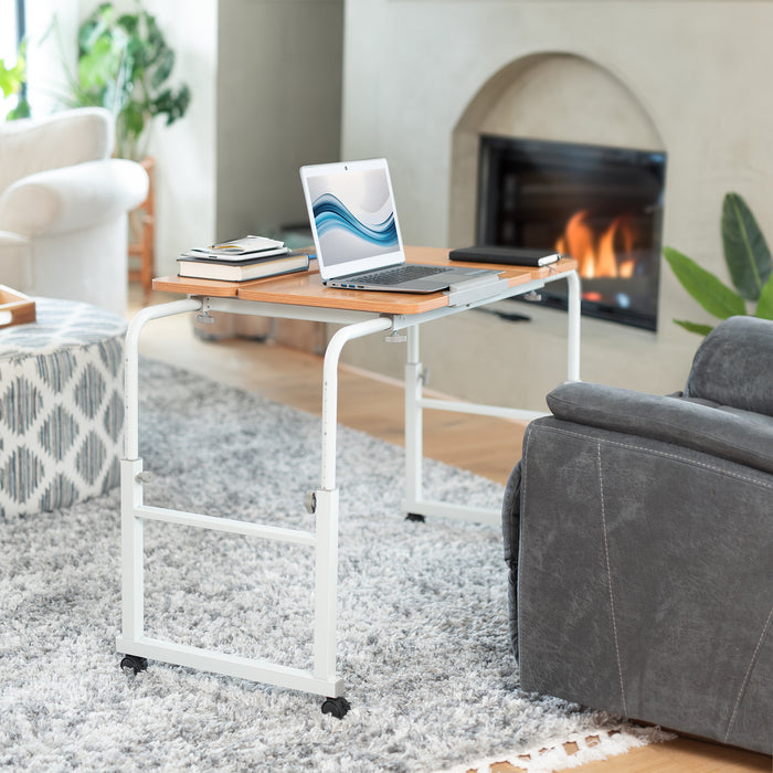 Laptop on a portable table in a living room with a fireplace and sofa.
