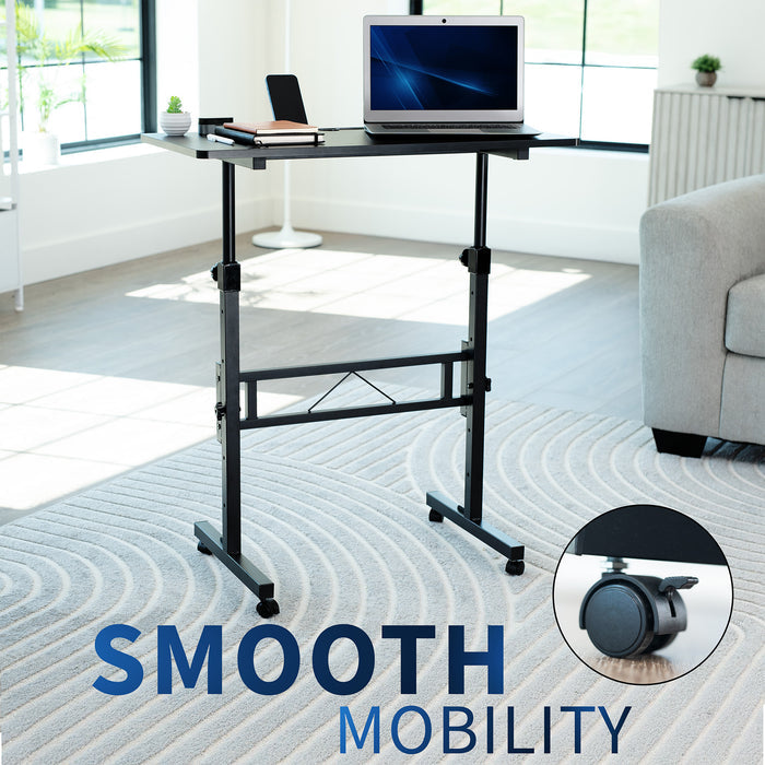 Adjustable standing desk with laptop on a carpeted floor in a room with a couch and windows.