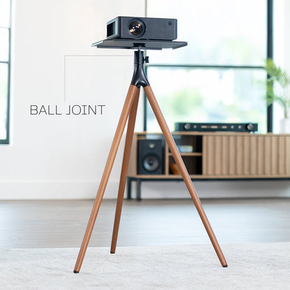 Projector on a wooden tripod in a room with furniture and decor.