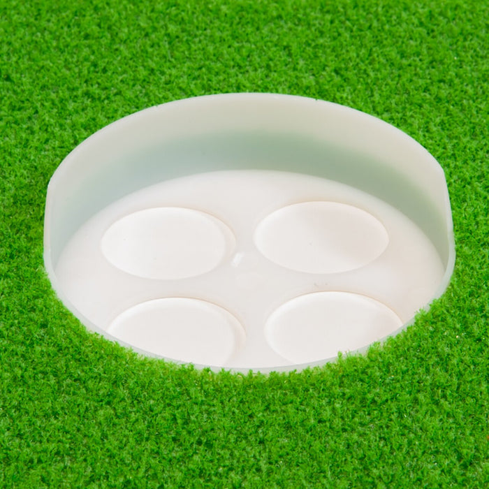 A close-up of the BirdieBall High Back Putting Green Cup (1/2" deep) embedded in artificial turf, showing four circular indentations inside the cup as part of the BirdieBall putting system.