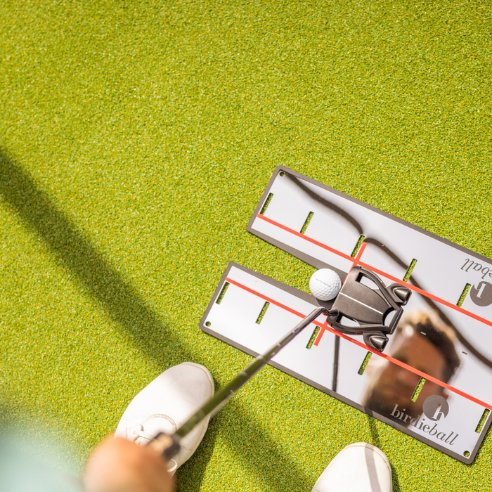 A golfer uses the BirdieBall Putting Mirror to line up a putter and ball on green turf, improving alignment with this precision golf training aid.