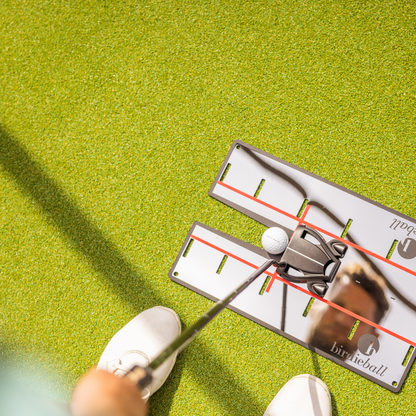 A golfer uses the BirdieBall Putting Mirror to line up a putter and ball on green turf, improving alignment with this precision golf training aid.