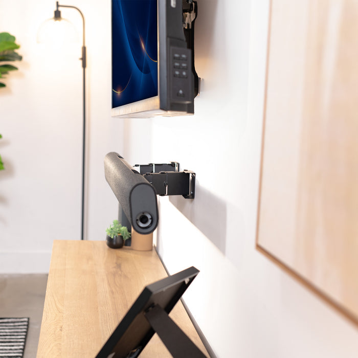 sound bar wall mount on a white wall with a desk and lamp in the foreground.